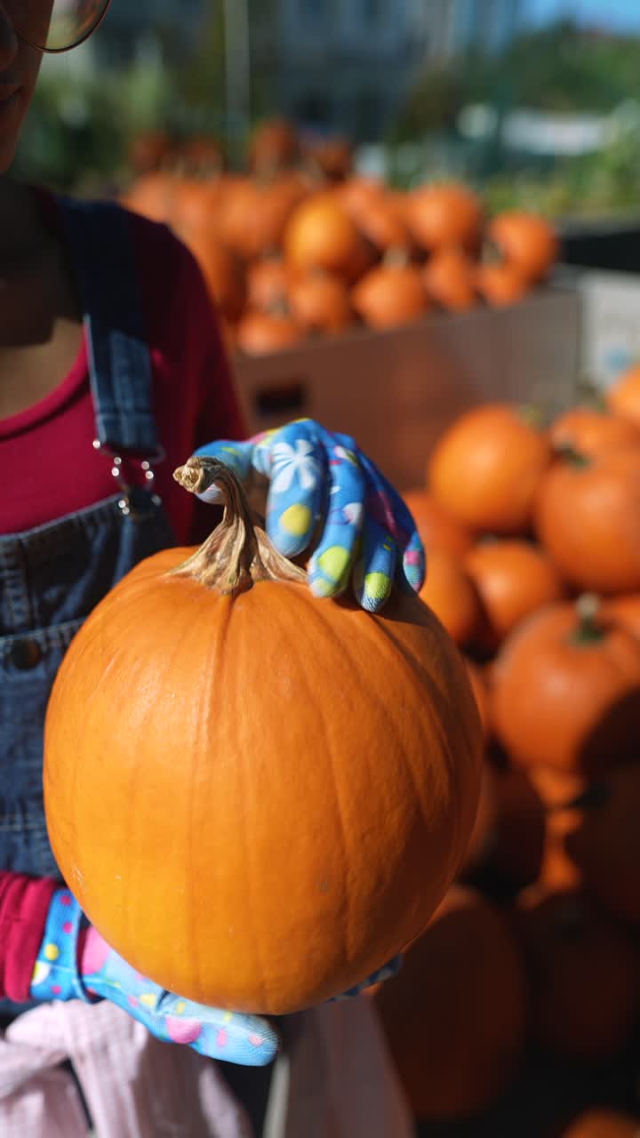 persona sosteniendo una calabaza en un mercado de otoño