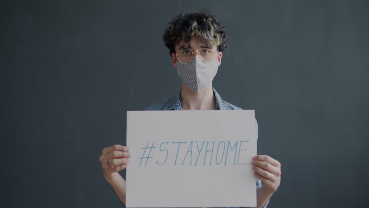Person holding a sign with the message "Stay Home"