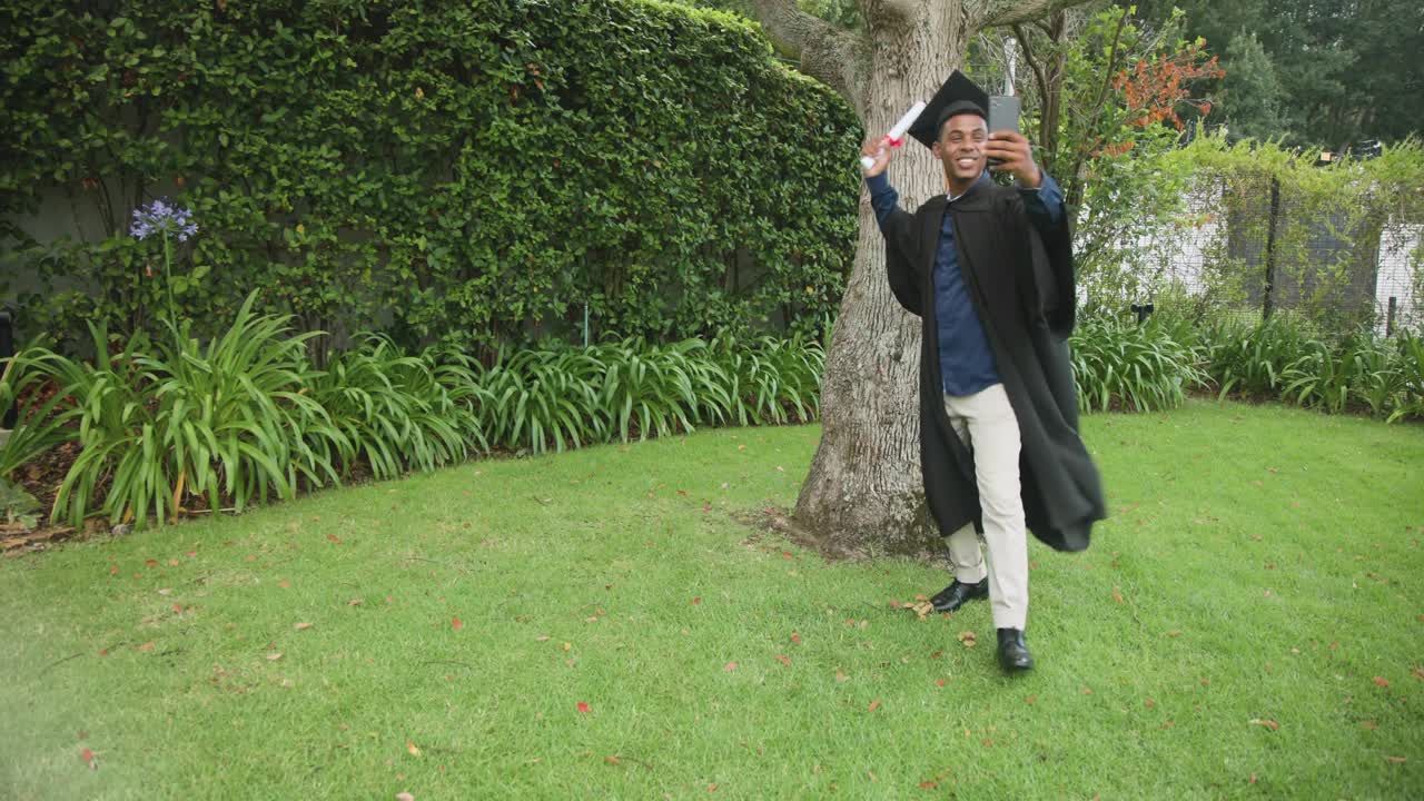 Male grad holding phone diploma for graduation, raising phone causing app icons drifting around him
