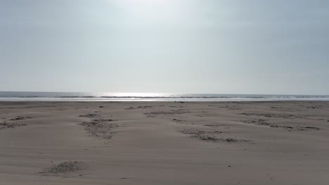 Low-angle-aerial-dolly-shot-in-front-of-the-beach-of-caleta-vidal-in-peru-with-dry-beach-sand-and-a-view-of-the-sea-during-a-cloudless-summer-day