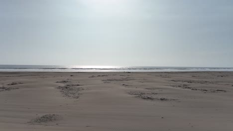 low angle aerial dolly shot in front of the beach of caleta vidal in peru with dry beach sand and a view of the sea during a cloudless summer day