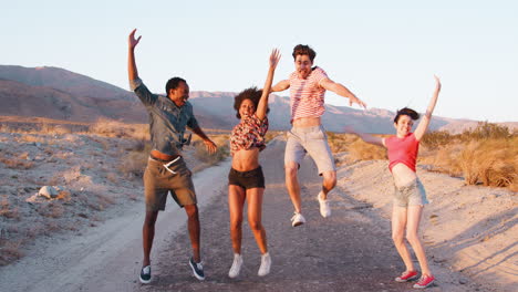 young adult friends jumping in the air on a desert road