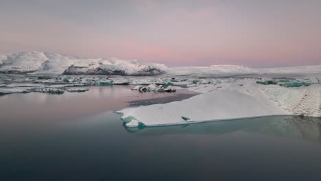 Rosafarbener-Sonnenaufgangshimmel-Und-Eisberge,-Die-Sich-über-Den-Gletschersee-Jökulsarlon-Spiegeln