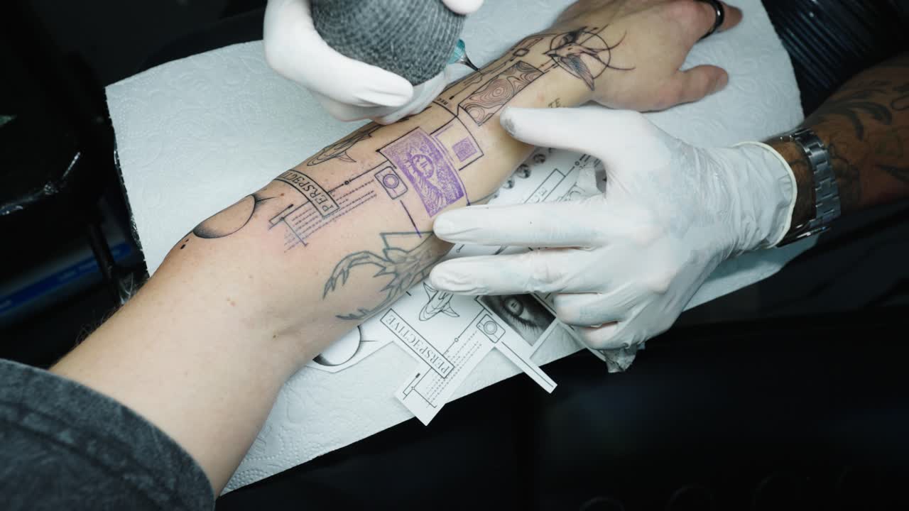 Close up of client arm get tattoo of illustrative style art with sample by side