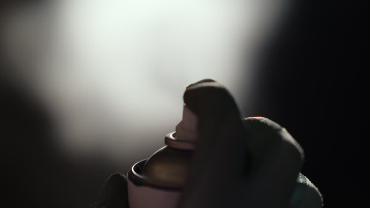 스프레이 캔이 있는 손은 검정색 배경에 스프레이할 수 있습니다.