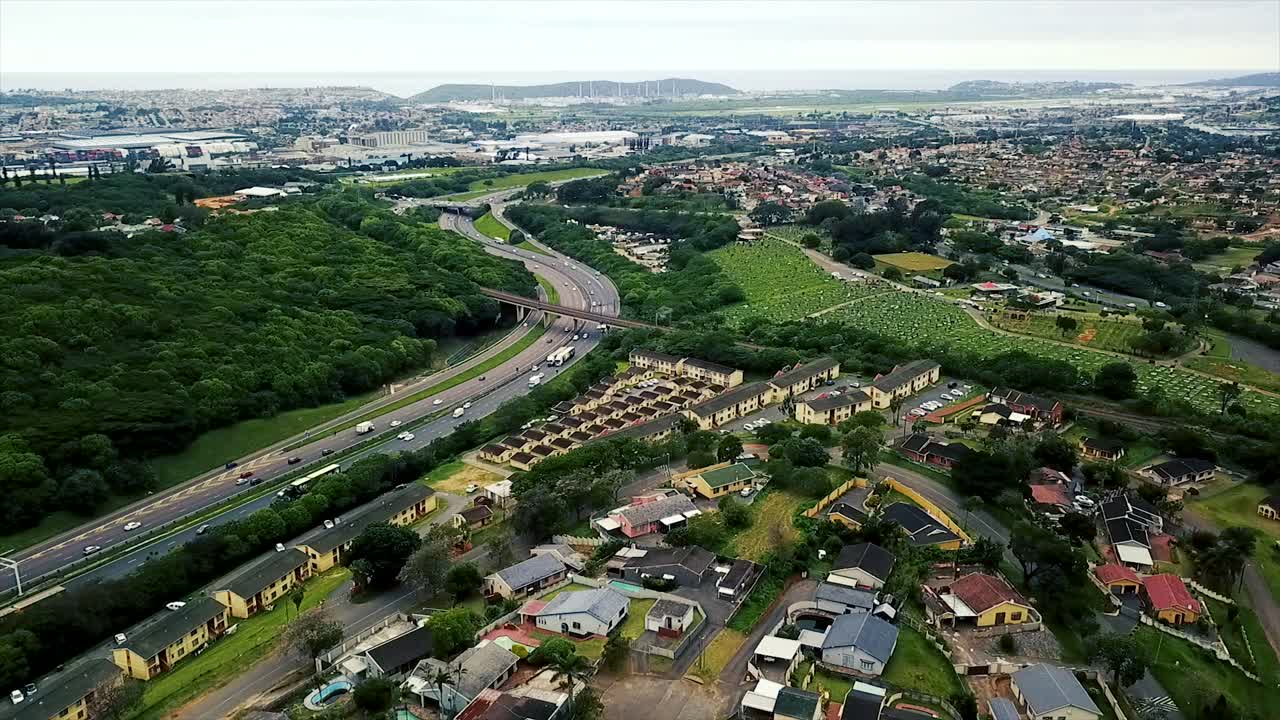 imágenes aéreas de un avión no tripulado volando sobre casas residenciales con vistas a una autopista concurrida con tráfico en movimiento en un suburbio de yellow wood park durban