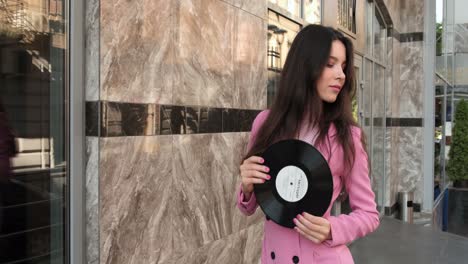 modelo posando con un disco en la calle cerca de una tienda de música