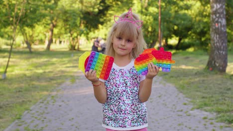 Smiling-child-girl-kid-holding-squeezing-anti-stress-pop-it-touch-screen-toys-simple-dimple-game