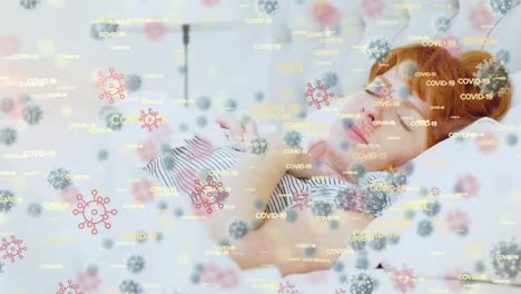 animation of macro covid-19 cells and cells icons floating over caucasian girl wiping her nose on be
