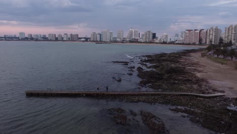 Pareja-Caminando-Por-El-Muelle-En-Un-Día-Nublado-En-La-Playa-De-Punta-Del-Este,-Uruguay,-Sudamérica