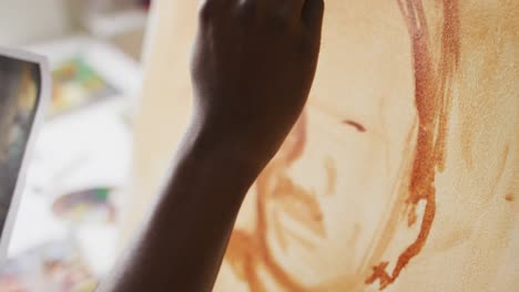 pintor afroamericano de sexo masculino pintando a partir de una fotografía en lienzo en el estudio del artista