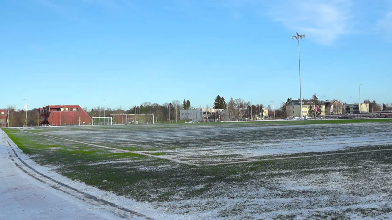 야그리 에스토니아의 겨울 동안 축구 경기장 또는 축구장, 초록색 축구 잔디 위에 눈이 쌓여있는 동안, 색 경계선이 보이고 축구 골이 배경에 있습니다.