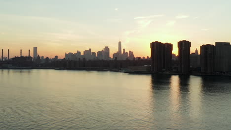 Absteigende-Luftaufnahmen-Von-Mehrfamilienhäusern-Am-Wasser-In-Der-Abenddämmerung.-Skyline-Mit-Wolkenkratzern-In-Der-Innenstadt-In-Der-Ferne.-Manhattan,-New-York-City,-Vereinigte-Staaten