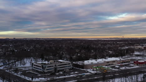 an aerial drone shot over a suburban neighborhood during a cloudy but golden sunrise, taken after a snow storm
