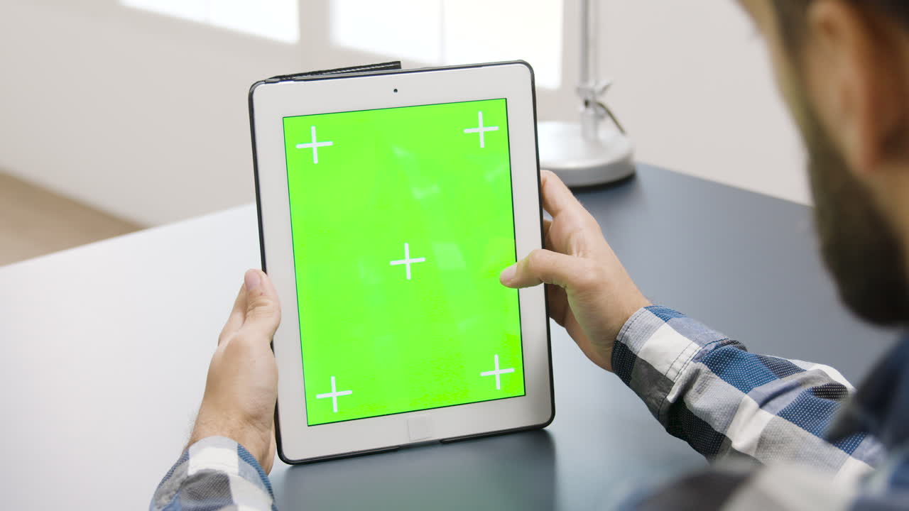 녹색 화면을 가진 태블릿을 사용하는 사람