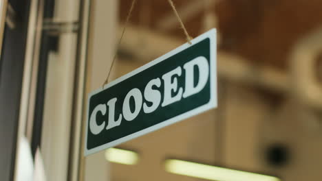 close-up view of young man turning over a open" signboard in coffee shop door"