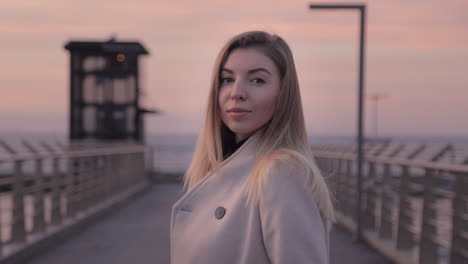 woman in a coat on a bridge at sunset