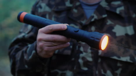 una mano con una linterna ilumina el camino en el bosque las gotas de niebla son visibles en un haz de luz