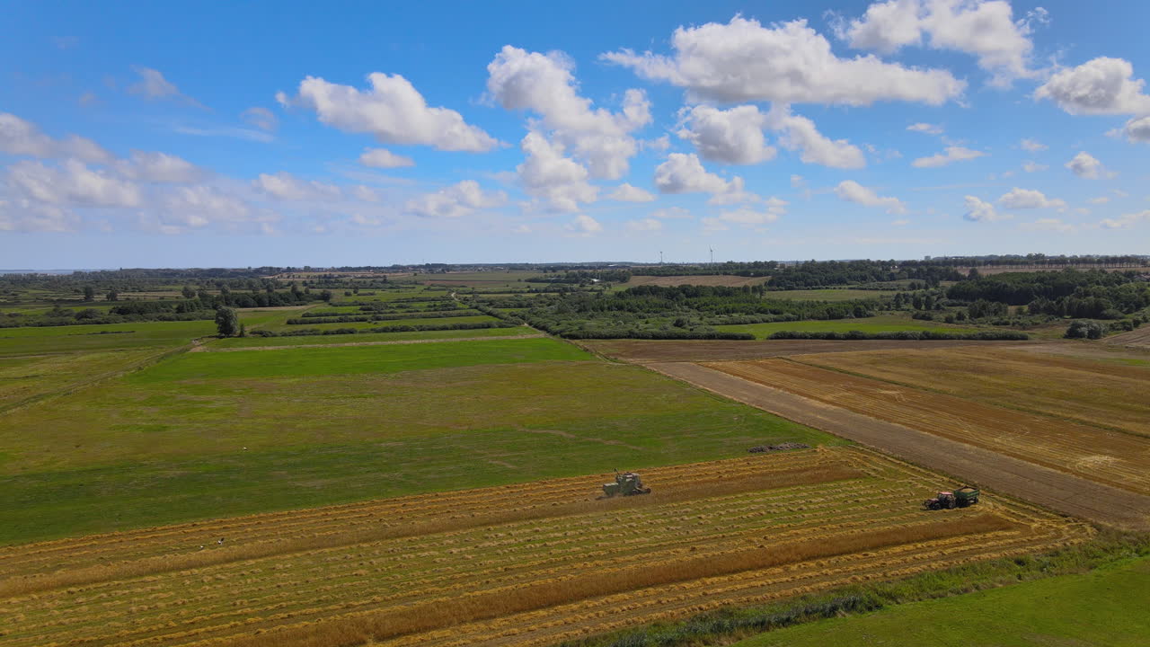 Aerial flight over agricultural field with working farm machines during beautiful summer day