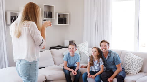 Family-Sitting-On-Sofa-At-Home-Playing-Charades