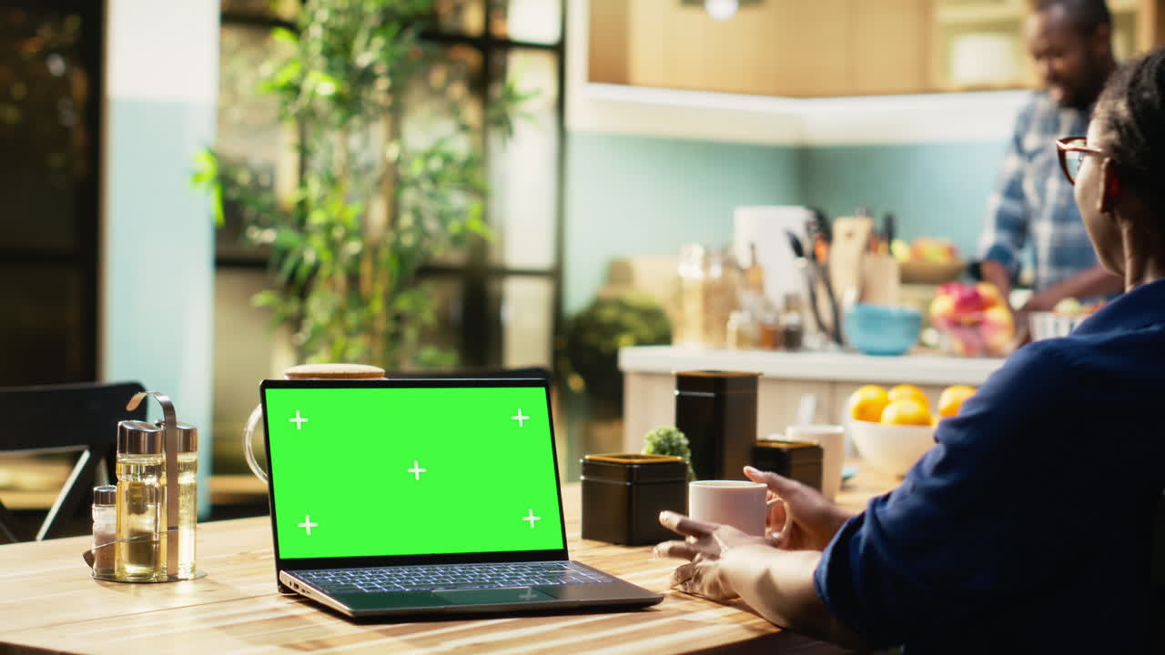 Person using a laptop with green screen at home