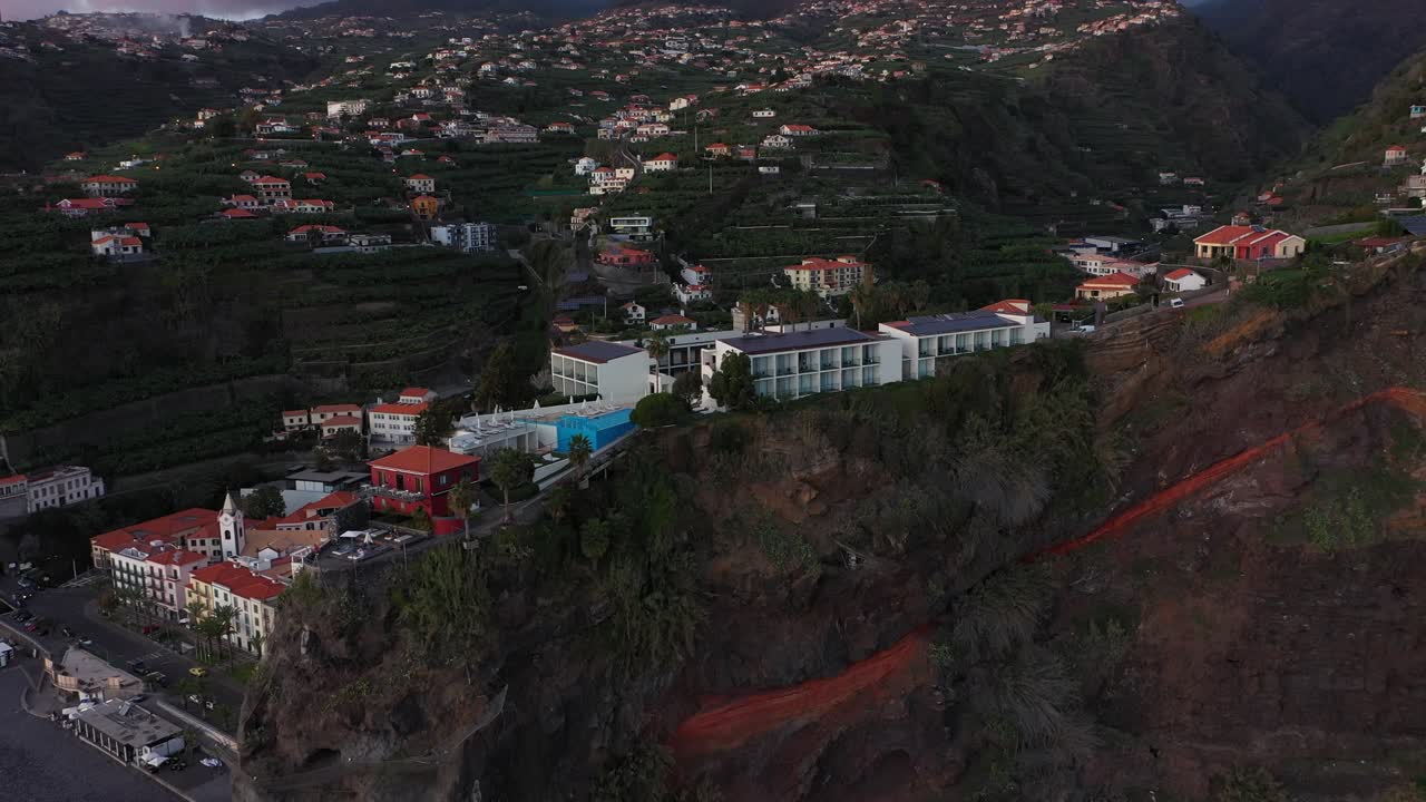 un dron que da vueltas a un hotel en la cima del acantilado en ponta do sol en madeira durante los últimos rayos de sol de la puesta de sol