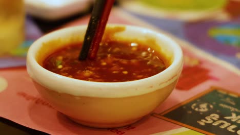 chopsticks stirring sauce in a small bowl