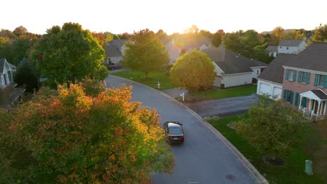 Schwarzes-Auto-Fährt-Während-Des-Herbstsonnenuntergangs-Durch-Die-Amerikanische-Nachbarschaft