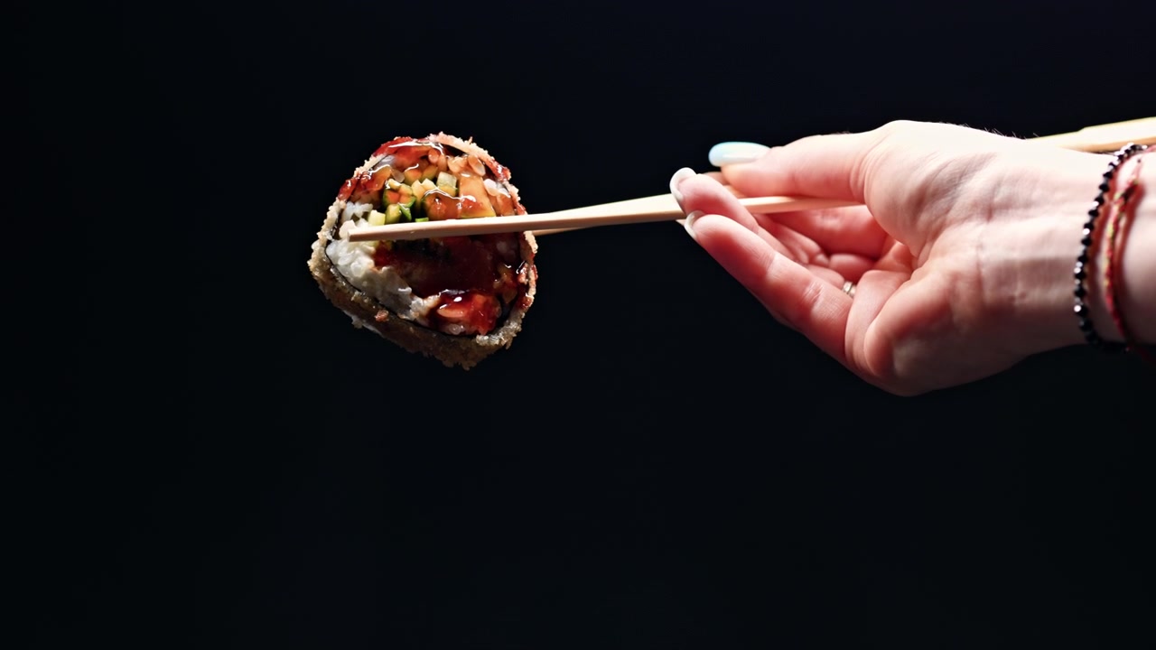 Eating sushi with chopsticks at a restaurant in the evening while enjoying a meal with friends and family