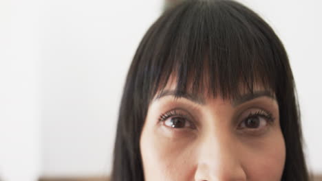 Portrait-close-up-of-eyes-of-happy-biracial-woman-smiling-at-home,-copy-space,-slow-motion