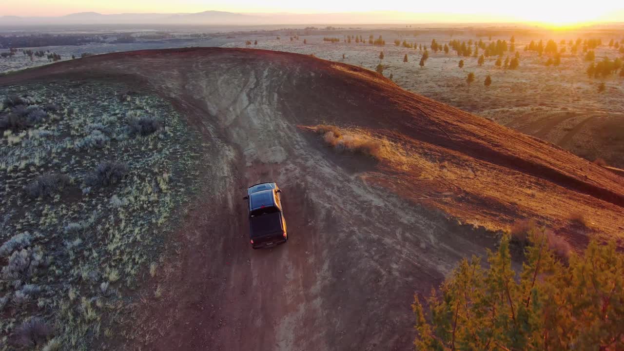girando desde arriba, el camión sube una colina todoterreno remota al amanecer 4k 60fps