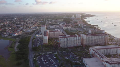 Cars-driving-down-the-highway-between-residential-homes-and-hotels-in-Aruba-during-sunset