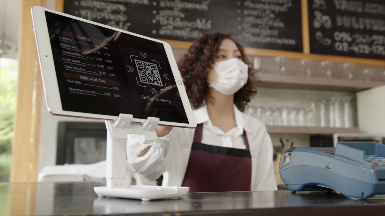 en el café, el personal del restaurante con máscara sugiere al cliente que use el menú en línea con código qr.