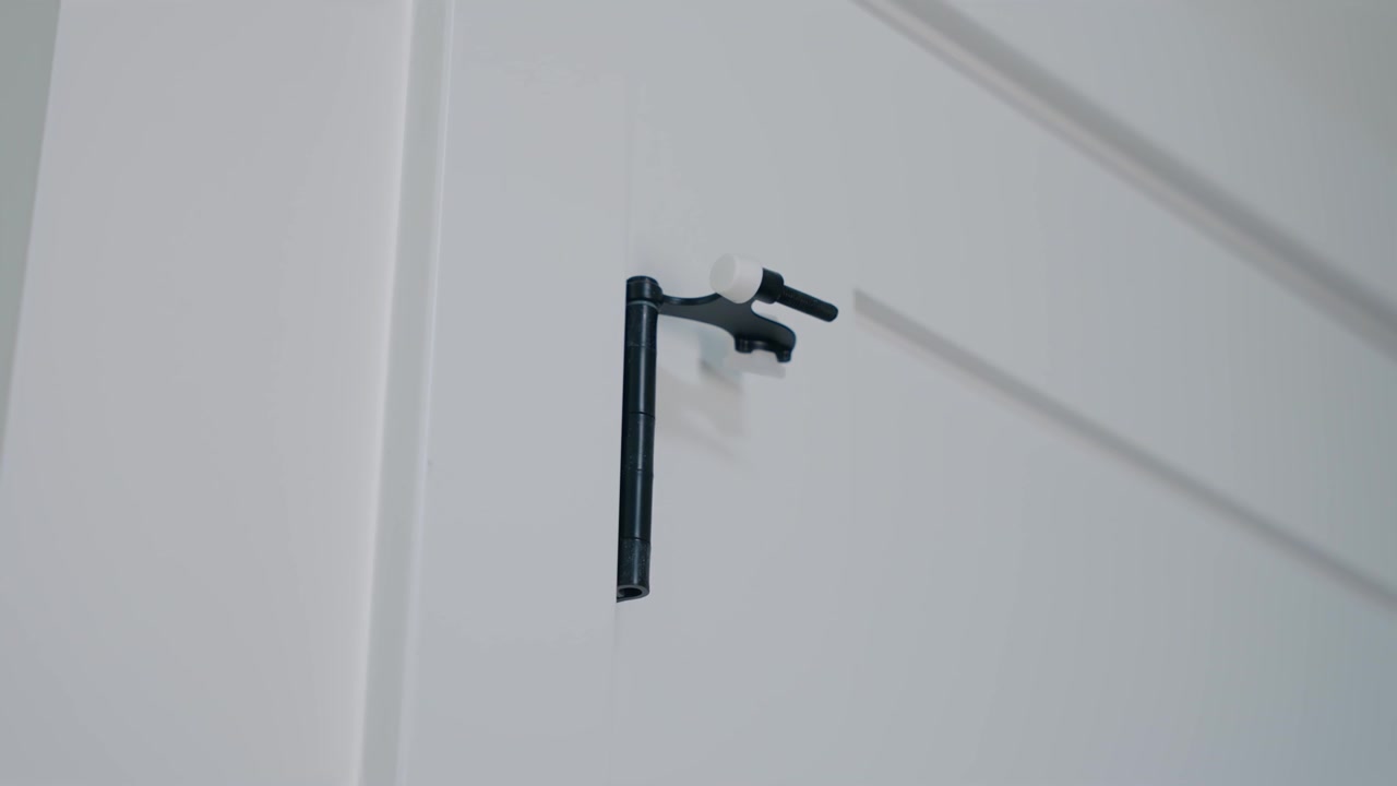 Slow motion handheld shot of black door stopper hardware mounted to a white interior closet door