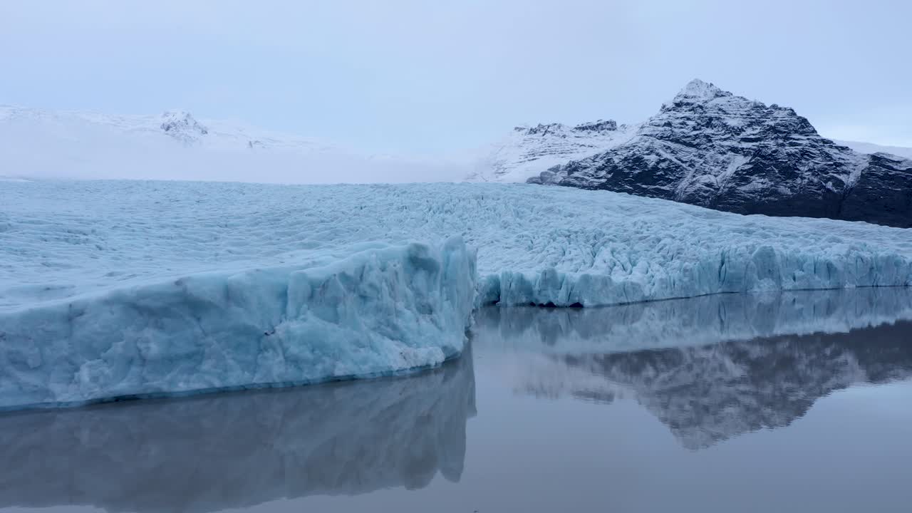 아이슬란드의 빙하 석호와 눈 덮인 산들을 배경으로 낮은 각도의 드론 비행