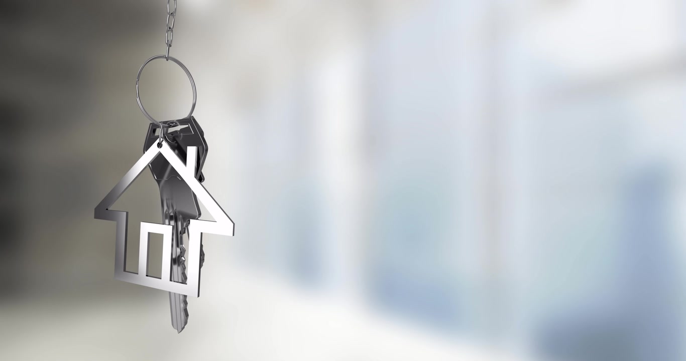 Portachiavi a forma di casa con chiavi appese su uno sfondo sfocato.