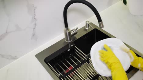 closeup of female hands washing dirty dishes in kitchen sink