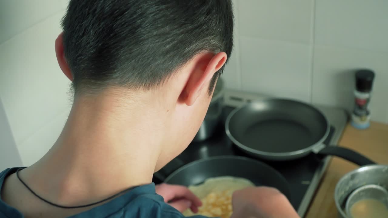 전기 스토브 에서 팬케이크 를 조리 하는 인식 할 수 없는 학교 소년