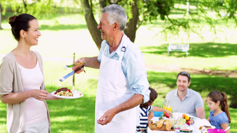 grandfather serving burgers at family barbecue