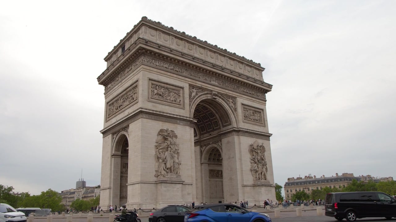 Inquadratura ampia dell'Arco di Trionfo con veicoli di passaggio e turisti a Parigi