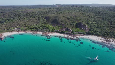 Luftaufnahme-Einer-Vorbeifahrenden-Yacht-Mit-Küste-Und-Straße-Im-Hintergrund,-Vorbeifahrende-Autos-An-Der-Eagle-Bay-Im-Westen-Australiens