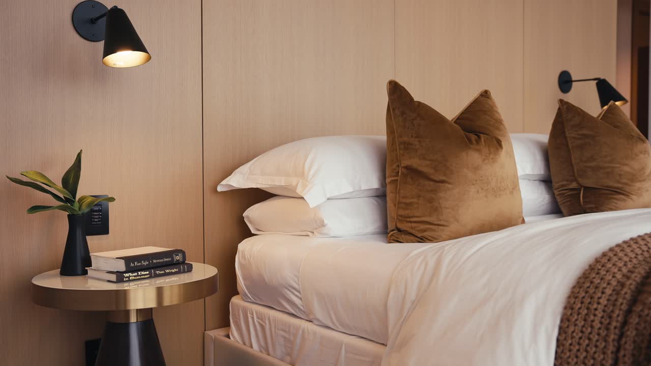 집의 침실에서 침대 램프와 테이블을 가진 끔하게 만들어진 침대의 단단한