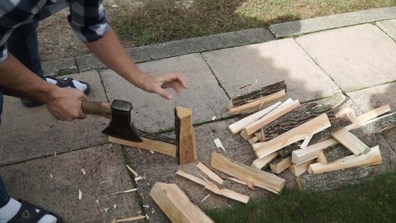 Young man is chopping wood in smaller pieces