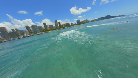 volando hacia hawaii cabeza de diamante, drone fpv sobre surfistas en waikiki con el horizonte de honolulu en el fondo
