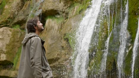 a male hiker in his 20s stops to admire one of the waterfalls along the route of the seven pools in catalonia spain - ruta dels set gorgs de campdevànol