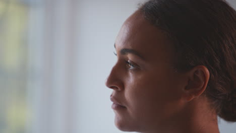 woman suffering with poor mental health in kitchen at home looking out of window