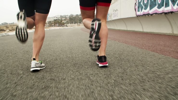 Caviglie e piedi di corridori che fanno jogging lungo la strada