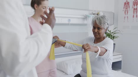 Diverse-male-doctor-talking-with-female-physiotherapist-and-happy-senior-female-patient,-slow-motion