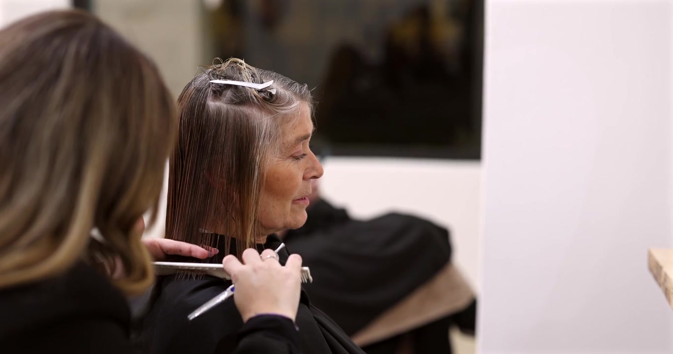 Professional Hairdresser Cutting Hair of Mature Woman in Salon