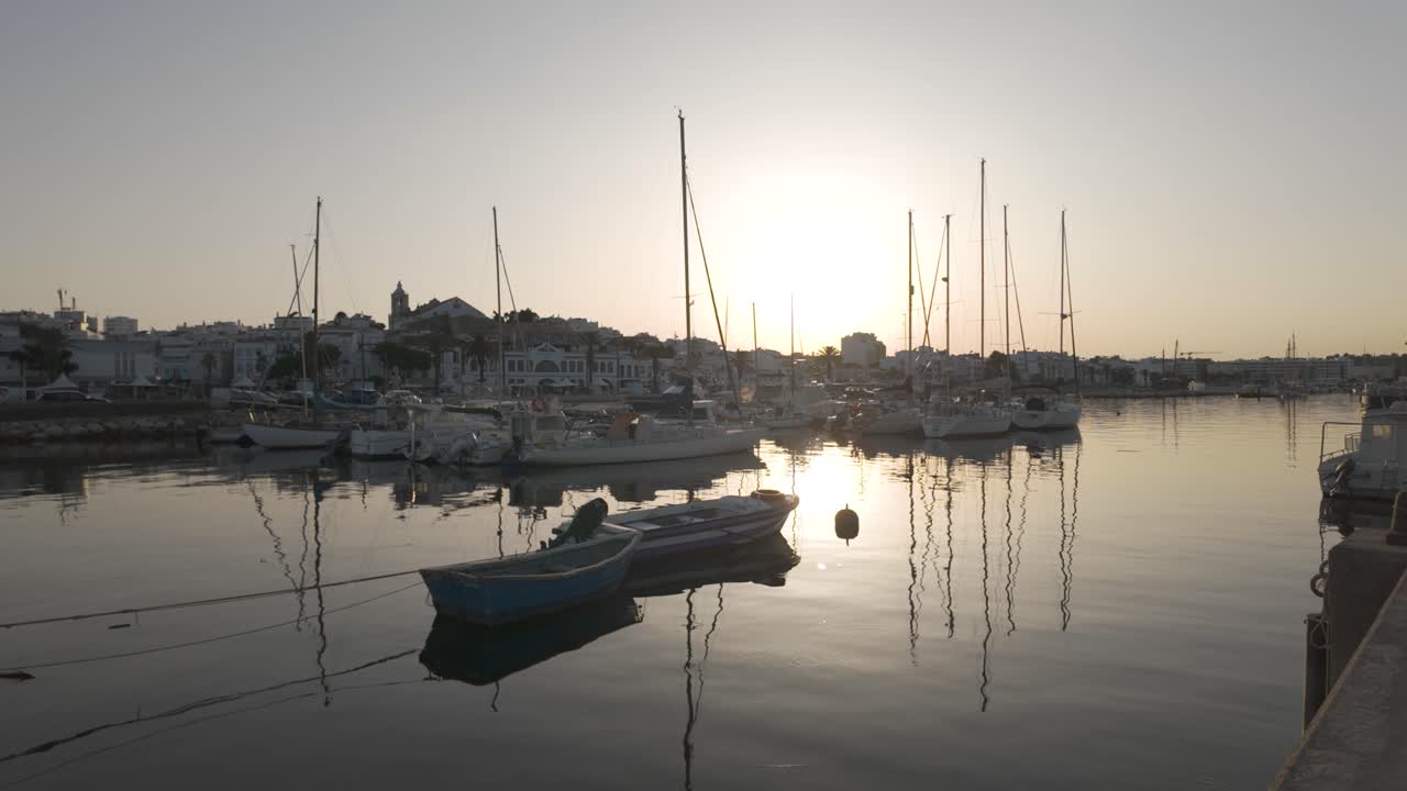 Sunset view of a fishing harbour in Lagos, Portugal, with boats and calm water reflection